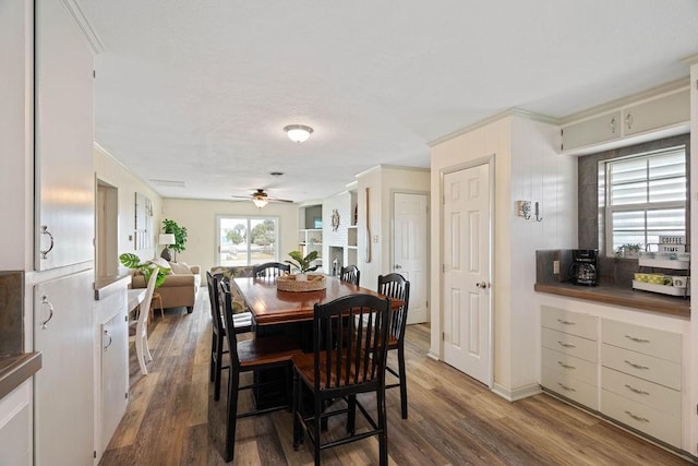 dining space with ceiling fan, wood finished floors, and crown molding