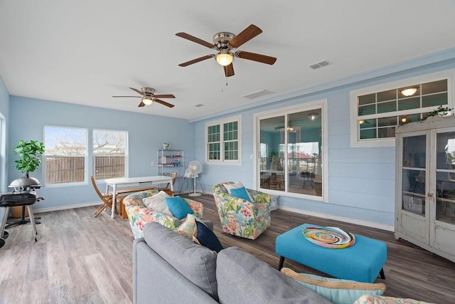 living area featuring baseboards, visible vents, and wood finished floors