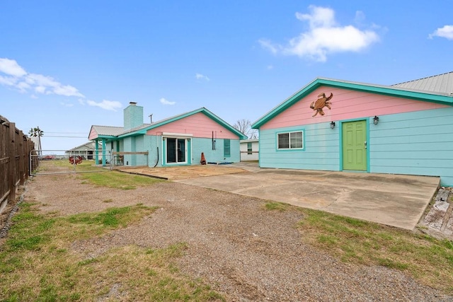 rear view of property featuring concrete driveway, a patio, and fence