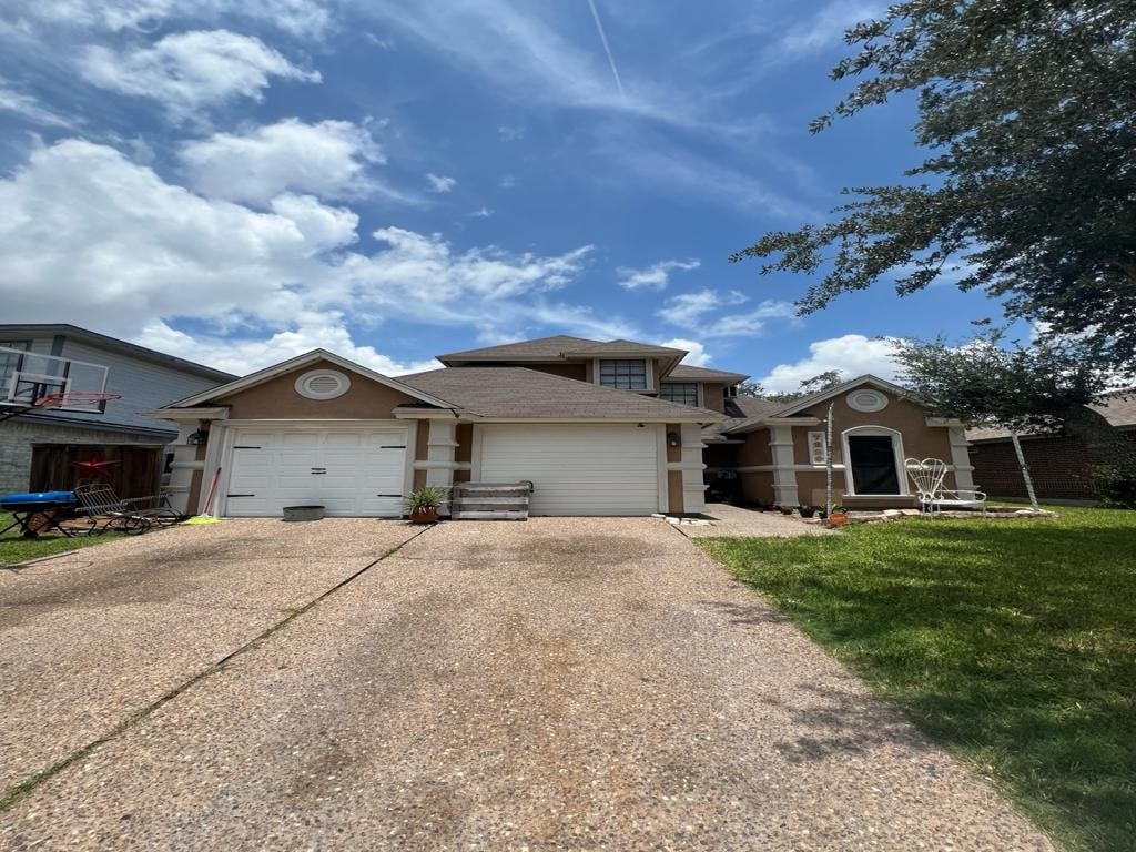 7229 Windy Ridge Dr, Corpus Christi, TX 78413 - view of front facade with concrete driveway, a garage, stucco siding, and a front yard