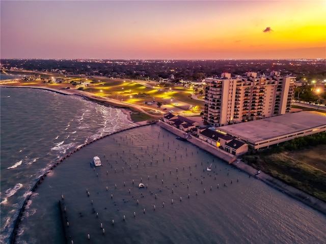 aerial view at dusk featuring a beach view and a water view