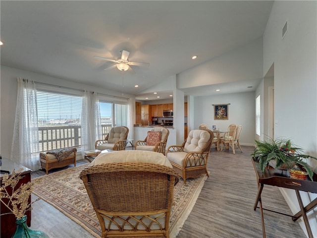 living room featuring light hardwood / wood-style floors, ceiling fan, and vaulted ceiling