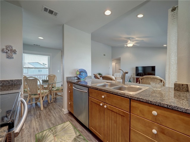 kitchen with sink, appliances with stainless steel finishes, dark stone countertops, hardwood / wood-style floors, and vaulted ceiling