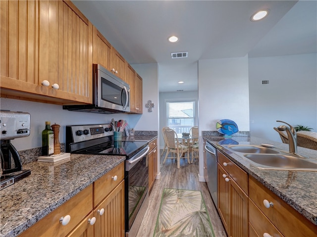 kitchen featuring stone counters, sink, light hardwood / wood-style flooring, and appliances with stainless steel finishes