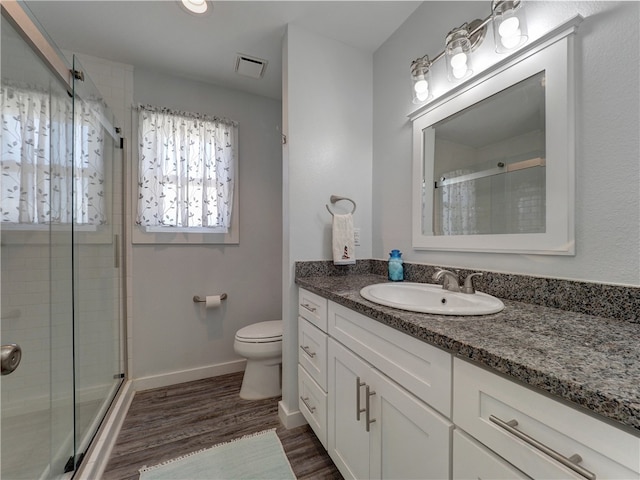 bathroom featuring toilet, an enclosed shower, vanity, and hardwood / wood-style flooring