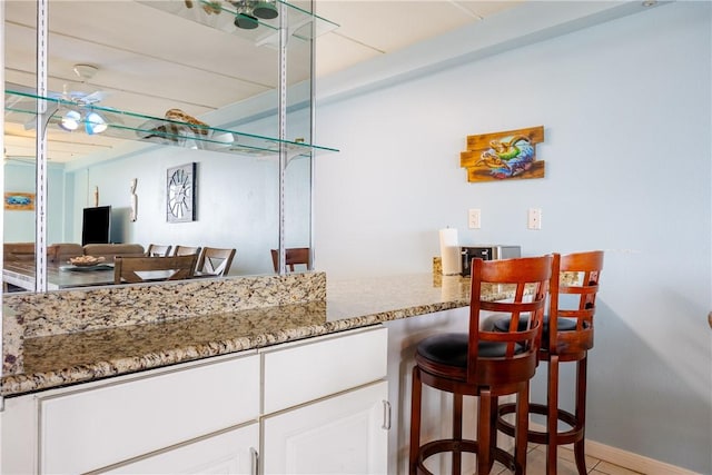 bar with white cabinets, light tile patterned floors, and stone countertops