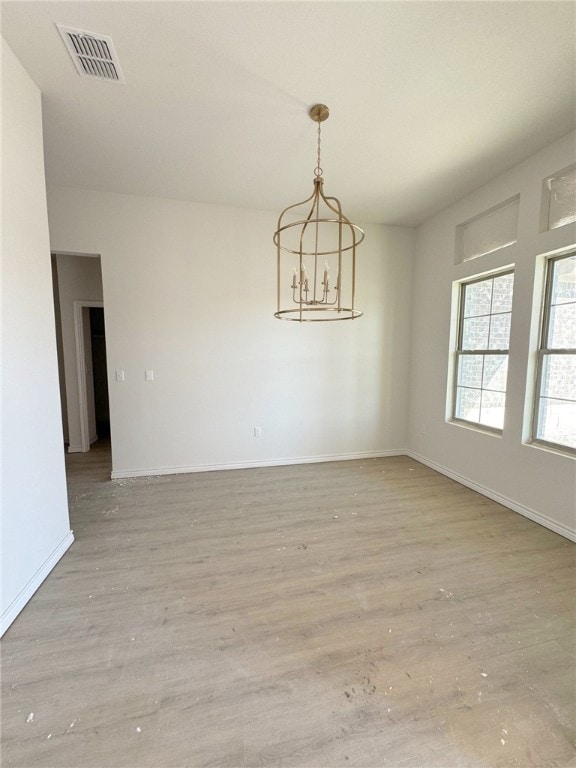 empty room with light hardwood / wood-style floors and an inviting chandelier