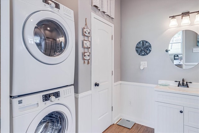 laundry area featuring stacked washing maching and dryer, light wood-type flooring, and sink