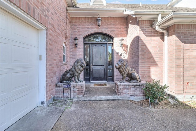 441 Colony Dr, Corpus Christi, TX 78412 - doorway to property featuring a garage, a shingled roof, driveway, and brick siding
