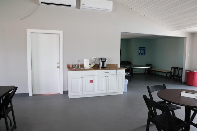 kitchen with lofted ceiling, sink, a wall unit AC, and white cabinets