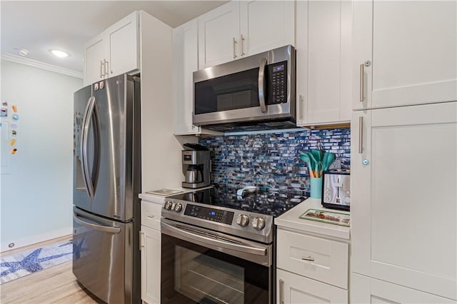 kitchen featuring crown molding, appliances with stainless steel finishes, tasteful backsplash, white cabinets, and light wood-type flooring