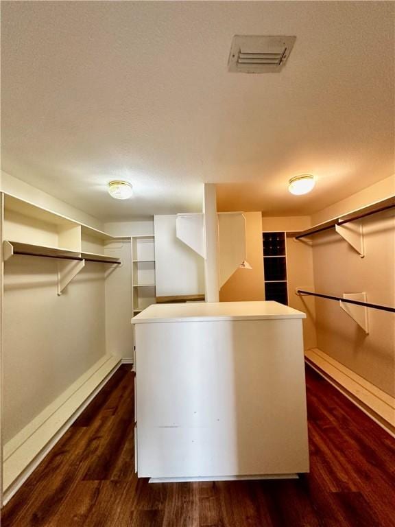 spacious closet with dark wood-style flooring and visible vents