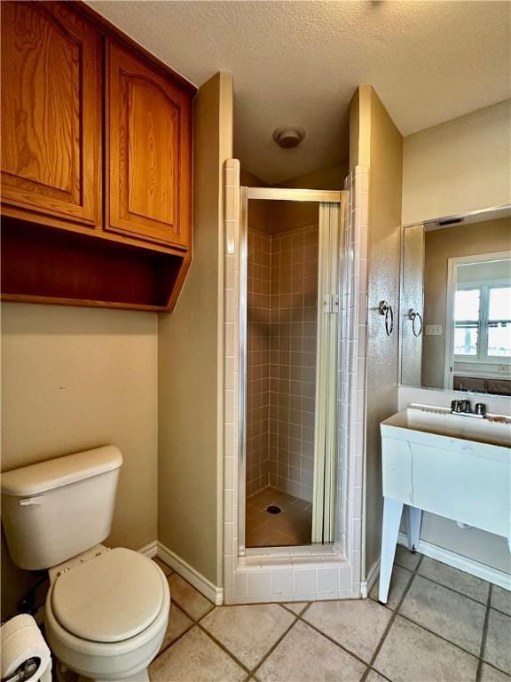 bathroom with a textured ceiling, a shower stall, toilet, and baseboards