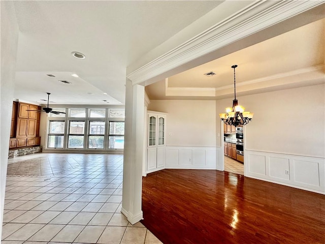 spare room with light tile patterned flooring, ceiling fan with notable chandelier, visible vents, ornamental molding, and a raised ceiling