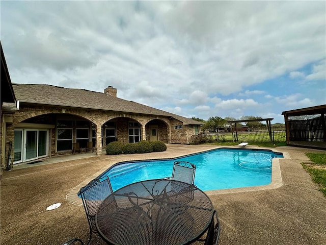 view of swimming pool featuring fence, a diving board, a fenced in pool, and a patio