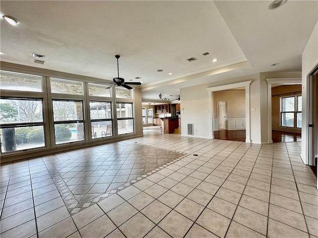 unfurnished living room featuring a ceiling fan, a raised ceiling, visible vents, and light tile patterned floors