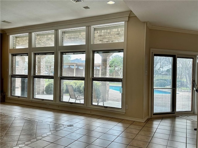 doorway with light tile patterned floors, ornamental molding, and baseboards