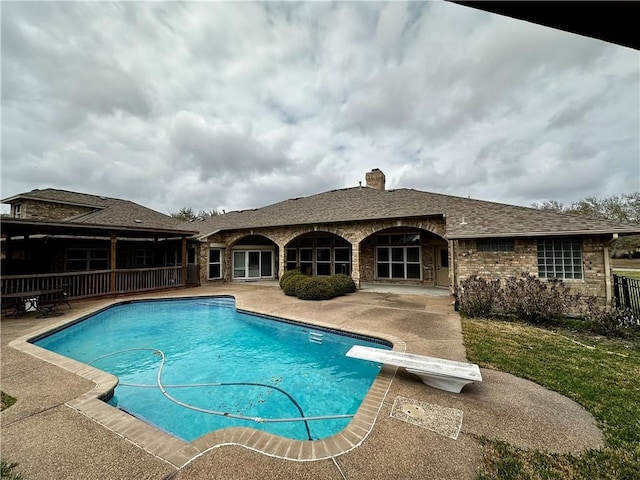 outdoor pool featuring a patio and a diving board