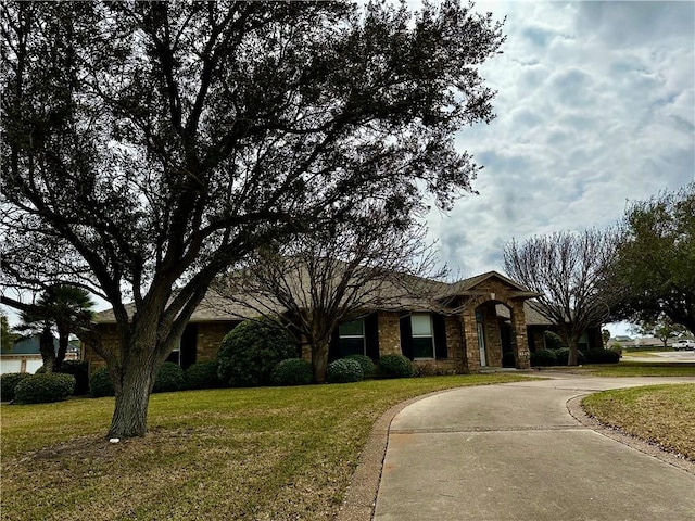 ranch-style home featuring a front yard and curved driveway