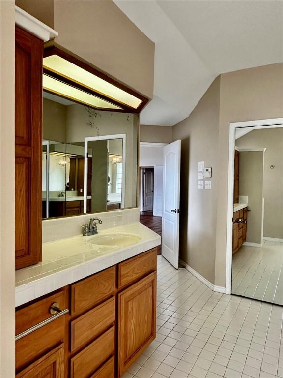 bathroom featuring baseboards, tasteful backsplash, vanity, and tile patterned floors