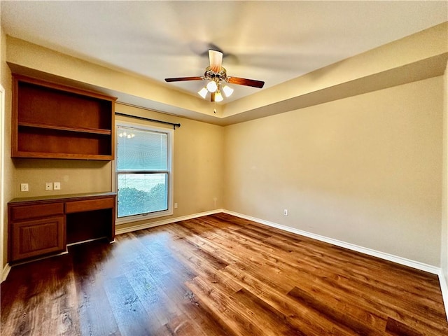 unfurnished office with ceiling fan, dark wood-style flooring, and baseboards