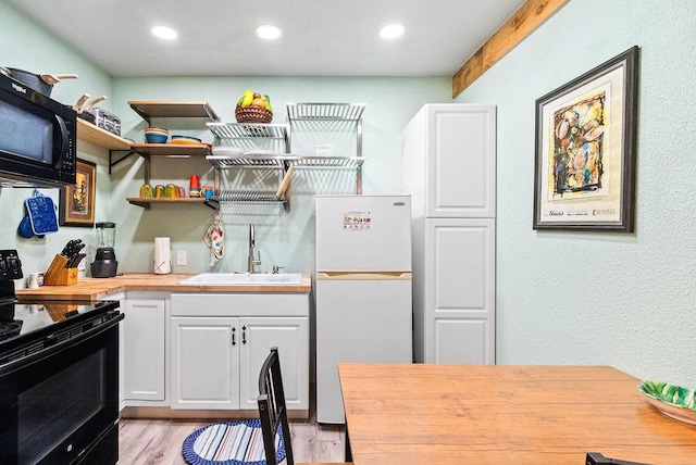 256 Melrose St, Corpus Christi, TX 78404 - kitchen featuring black appliances, wooden counters, light wood-type flooring, white cabinets, and recessed lighting
