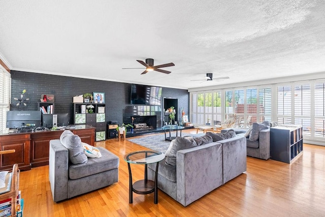 256 Melrose St, Corpus Christi, TX 78404 - living area featuring a fireplace, light wood-style floors, ceiling fan, a textured ceiling, and brick wall