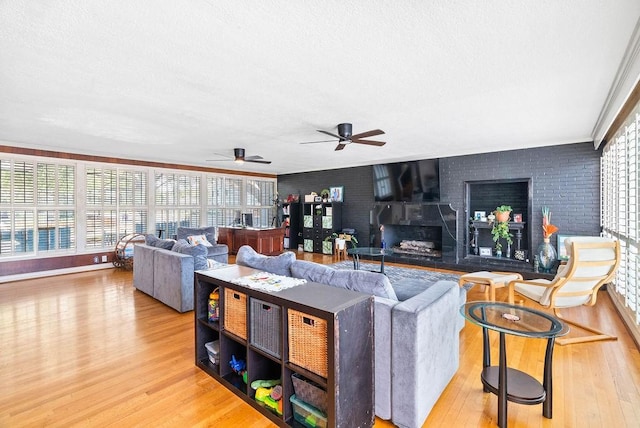 256 Melrose St, Corpus Christi, TX 78404 - living area featuring light wood finished floors, a textured ceiling, a fireplace, ceiling fan, and brick wall