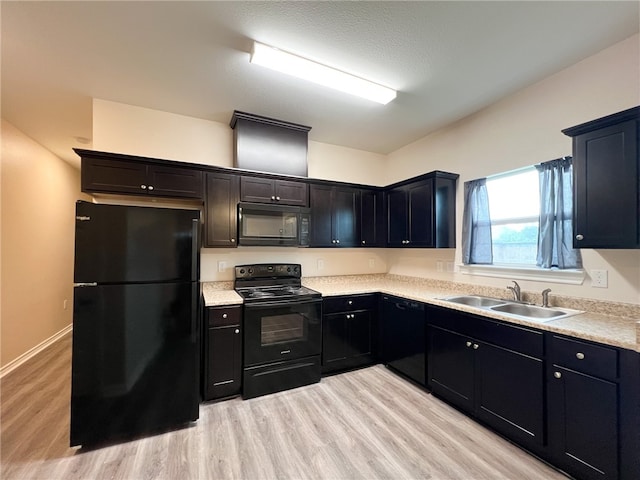 kitchen featuring black appliances, sink, light hardwood / wood-style floors, and a textured ceiling