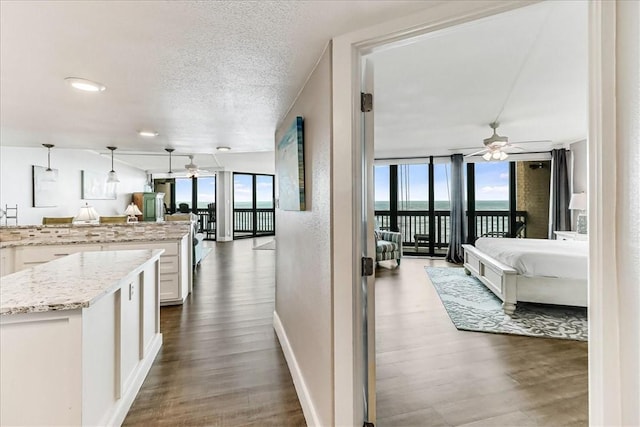 corridor with baseboards, a textured ceiling, and wood finished floors