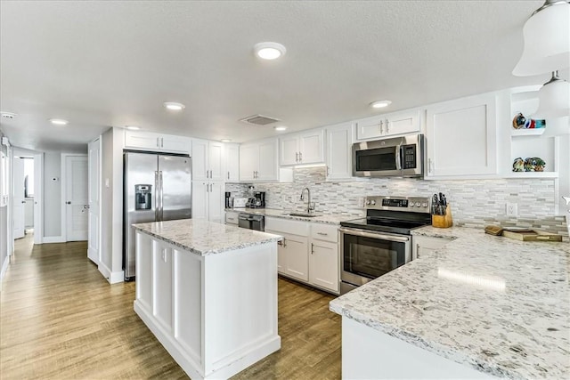 kitchen featuring open shelves, wood finished floors, a sink, white cabinets, and stainless steel appliances