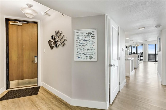 interior space with baseboards, a textured ceiling, and light wood-style flooring