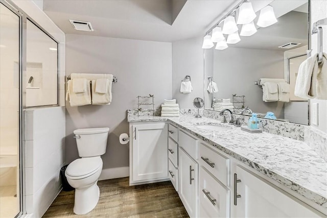 full bathroom featuring visible vents, vanity, wood finished floors, toilet, and a stall shower