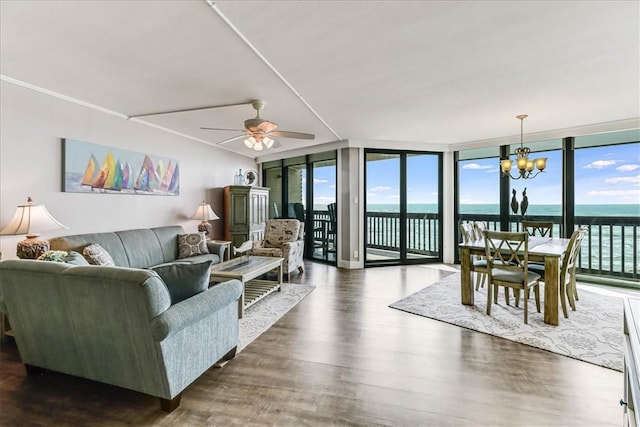 living area featuring expansive windows, a water view, ceiling fan with notable chandelier, and dark wood-style floors