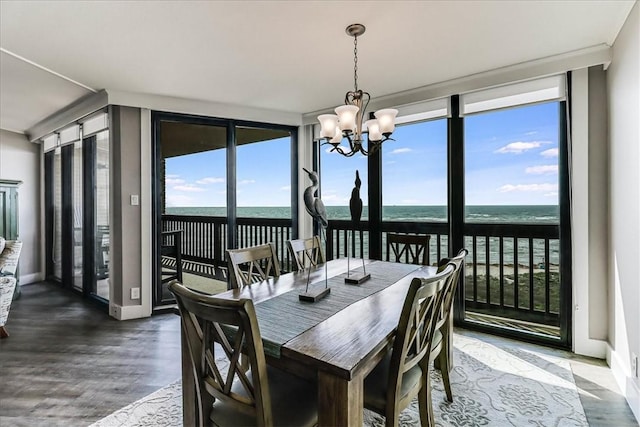 dining space featuring wood finished floors, a wall of windows, baseboards, a water view, and a notable chandelier