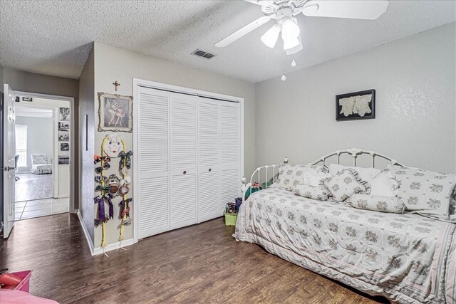 bedroom featuring ceiling fan, dark hardwood / wood-style floors, a textured ceiling, and a closet