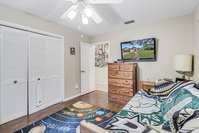 bedroom with a textured ceiling, a closet, ceiling fan, and dark hardwood / wood-style floors