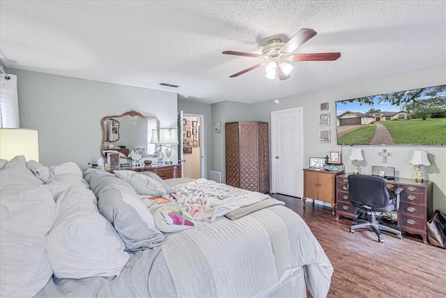 bedroom with a textured ceiling, ceiling fan, and dark wood-type flooring