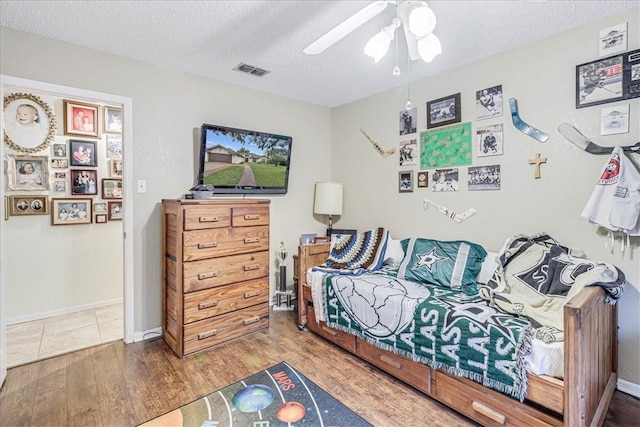 bedroom with hardwood / wood-style flooring, ceiling fan, and a textured ceiling