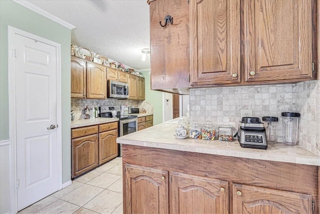 kitchen with tasteful backsplash, ornamental molding, a textured ceiling, stainless steel appliances, and light tile patterned flooring