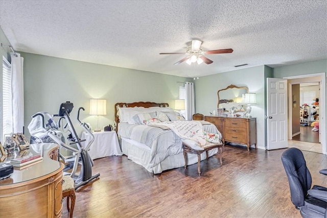 bedroom with ceiling fan, dark hardwood / wood-style floors, and a textured ceiling