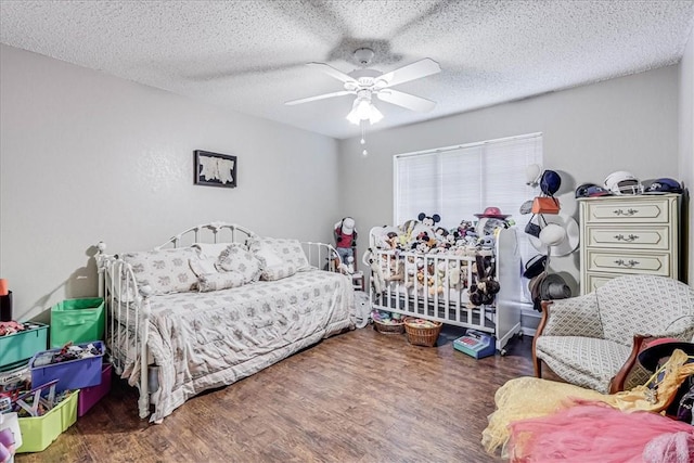 bedroom with a textured ceiling, ceiling fan, and dark wood-type flooring