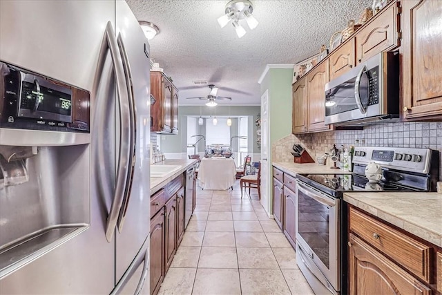 kitchen featuring appliances with stainless steel finishes, tasteful backsplash, ornamental molding, a textured ceiling, and light tile patterned floors