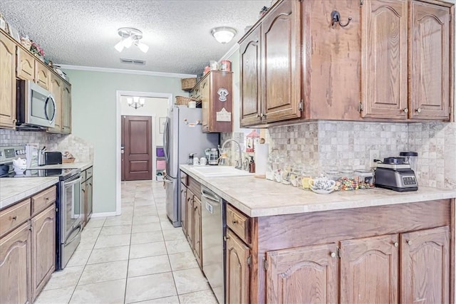 kitchen featuring a textured ceiling, stainless steel appliances, crown molding, sink, and light tile patterned flooring