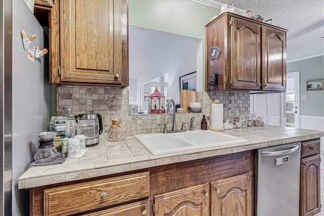 kitchen featuring sink, decorative backsplash, ornamental molding, a textured ceiling, and stainless steel appliances