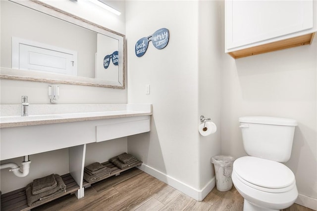 bathroom with hardwood / wood-style flooring, toilet, and sink