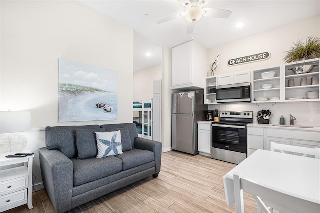 kitchen with appliances with stainless steel finishes, sink, white cabinets, and light hardwood / wood-style floors