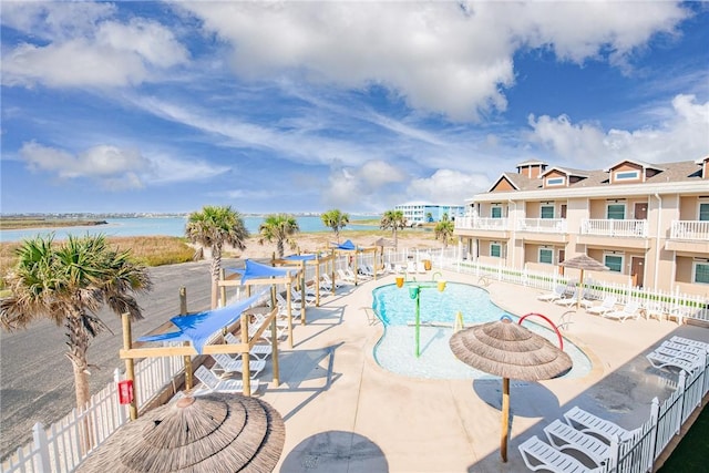 view of swimming pool featuring a water view and a patio