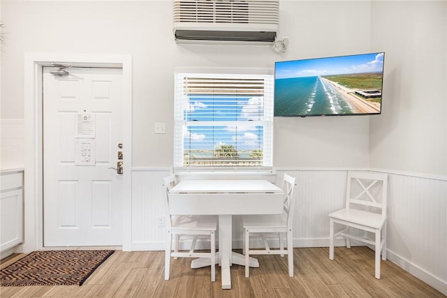 dining area with a wall mounted AC and light wood-type flooring