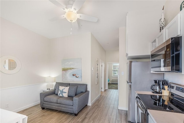 kitchen featuring appliances with stainless steel finishes, white cabinets, decorative backsplash, ceiling fan, and light hardwood / wood-style flooring